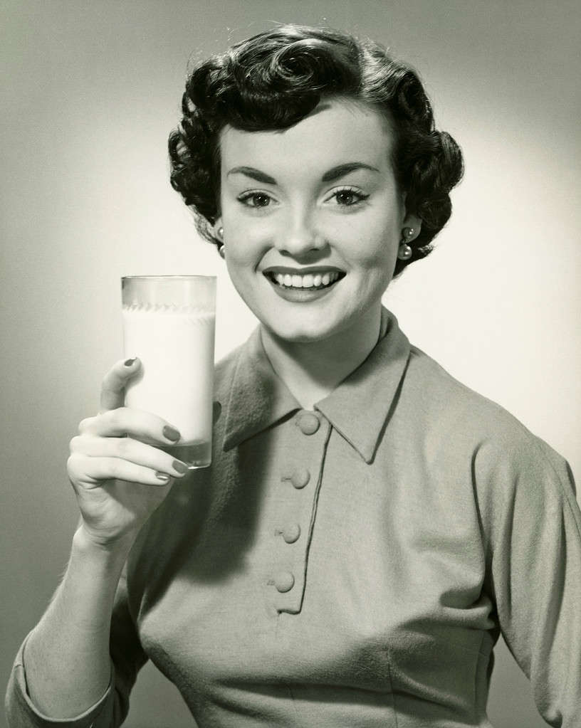 Giovane donna che tiene un bicchiere di latte, (B&W), ritratto