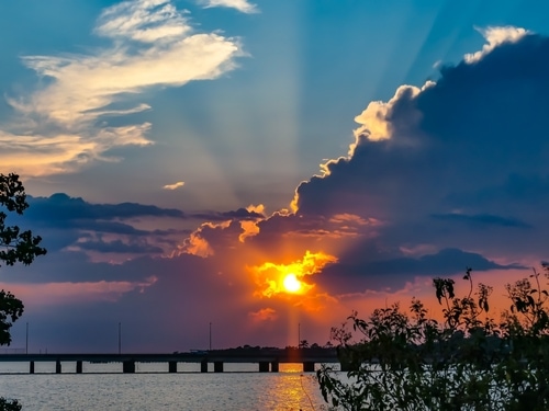 Bellissimo tramonto sul lago Pontchartrain e sul ponte della strada rialzata.  Riflessi colorati nell'acqua.