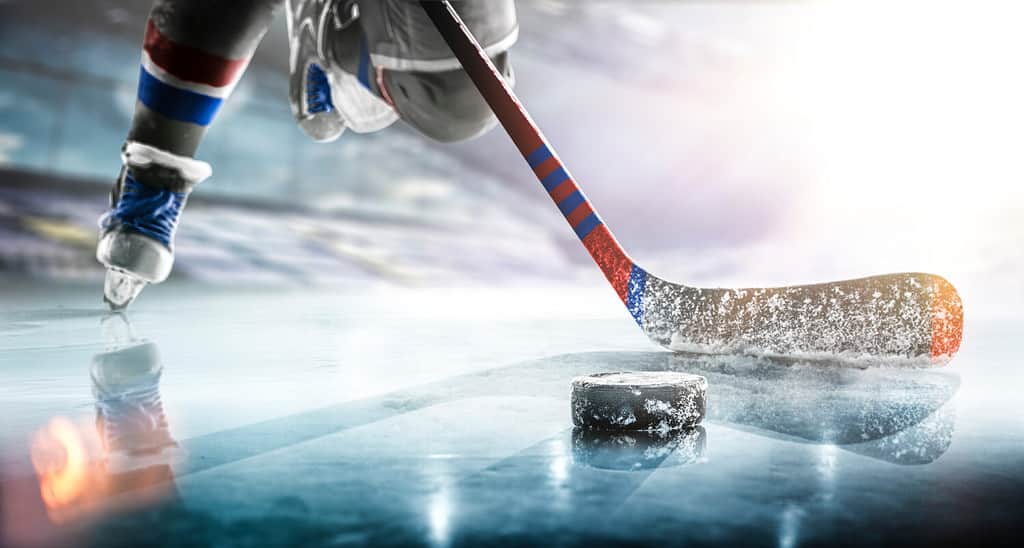 Primo piano del bastone da hockey su ghiaccio sulla pista di pattinaggio in posizione per colpire il disco da hockey.