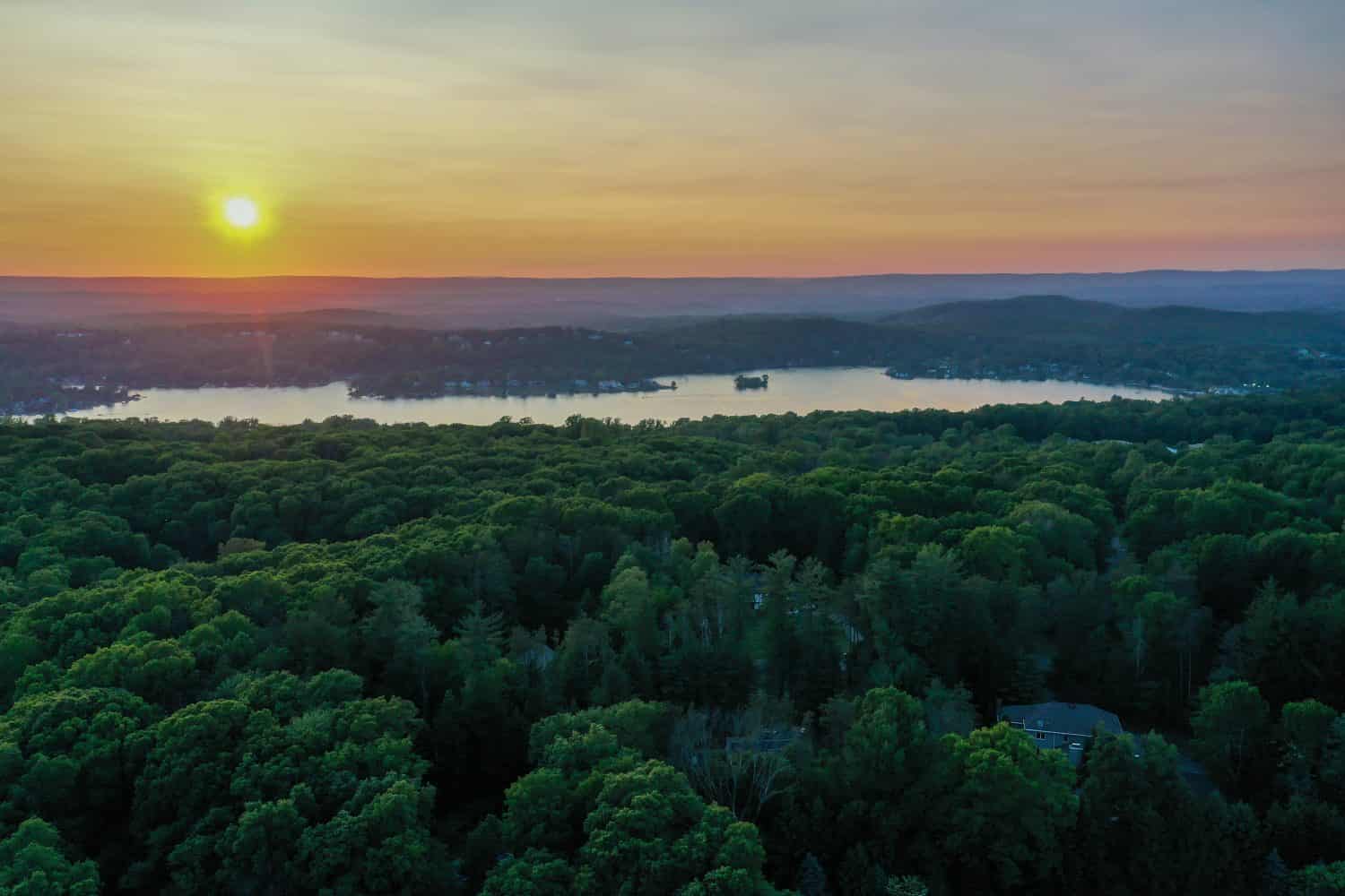 Bellissimo tramonto su foreste lussureggianti e sul Lago Mohawk a Sparta NJ in lontananza in tarda primavera aerea