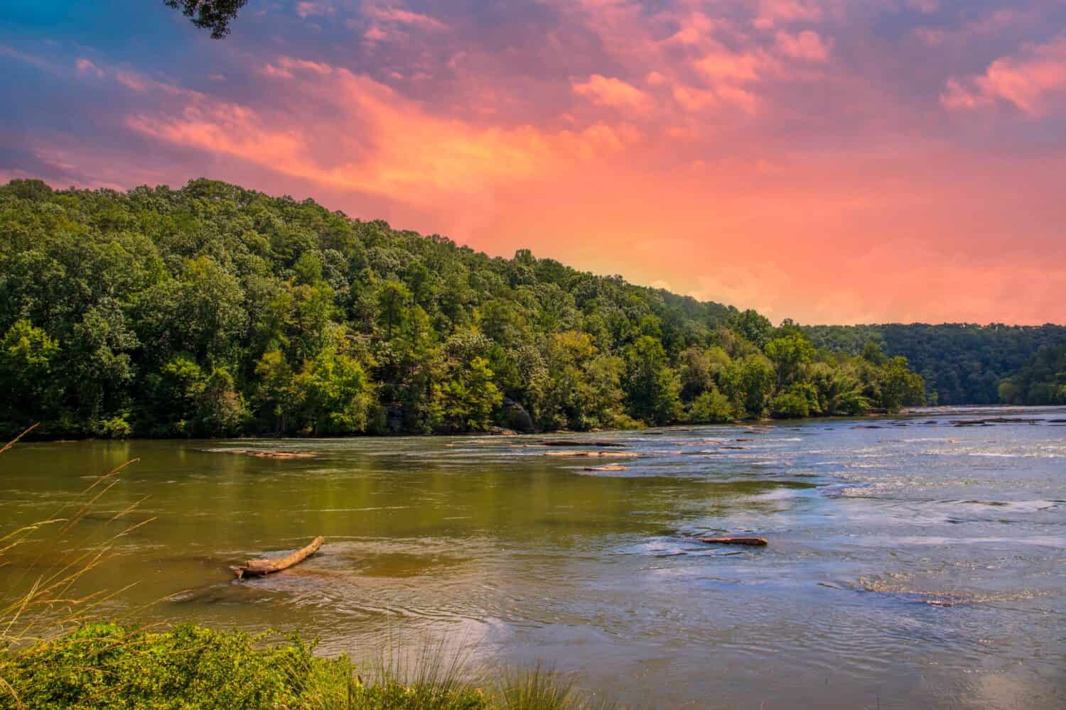 uno splendido paesaggio estivo lungo il fiume Chattahoochee con acqua corrente circondata da rigogliosi alberi verdi, erba e piante con potenti nuvole al tramonto ad Atlanta Georgia USA