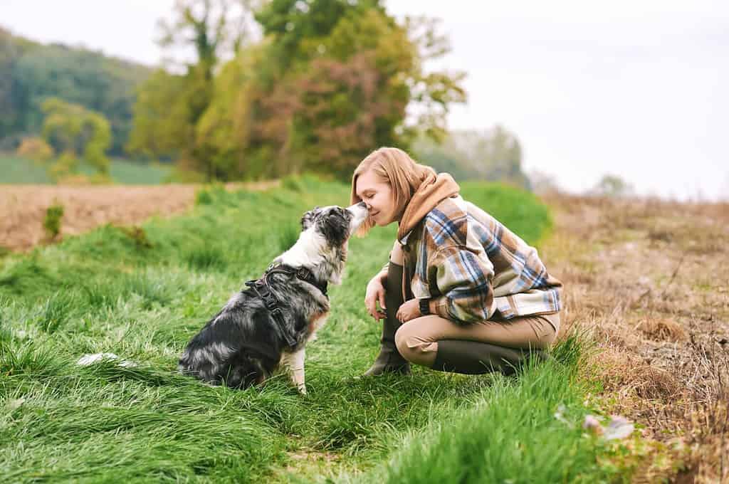 Ritratto all'aperto di bella giovane donna che gioca con il cane da pastore australiano