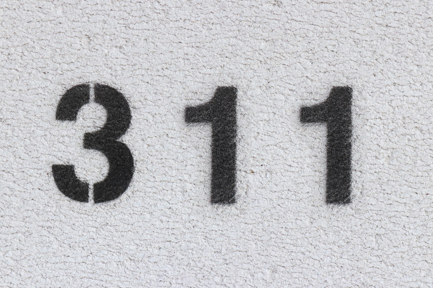 Numero nero 311 sul muro bianco.  Vernice spray.