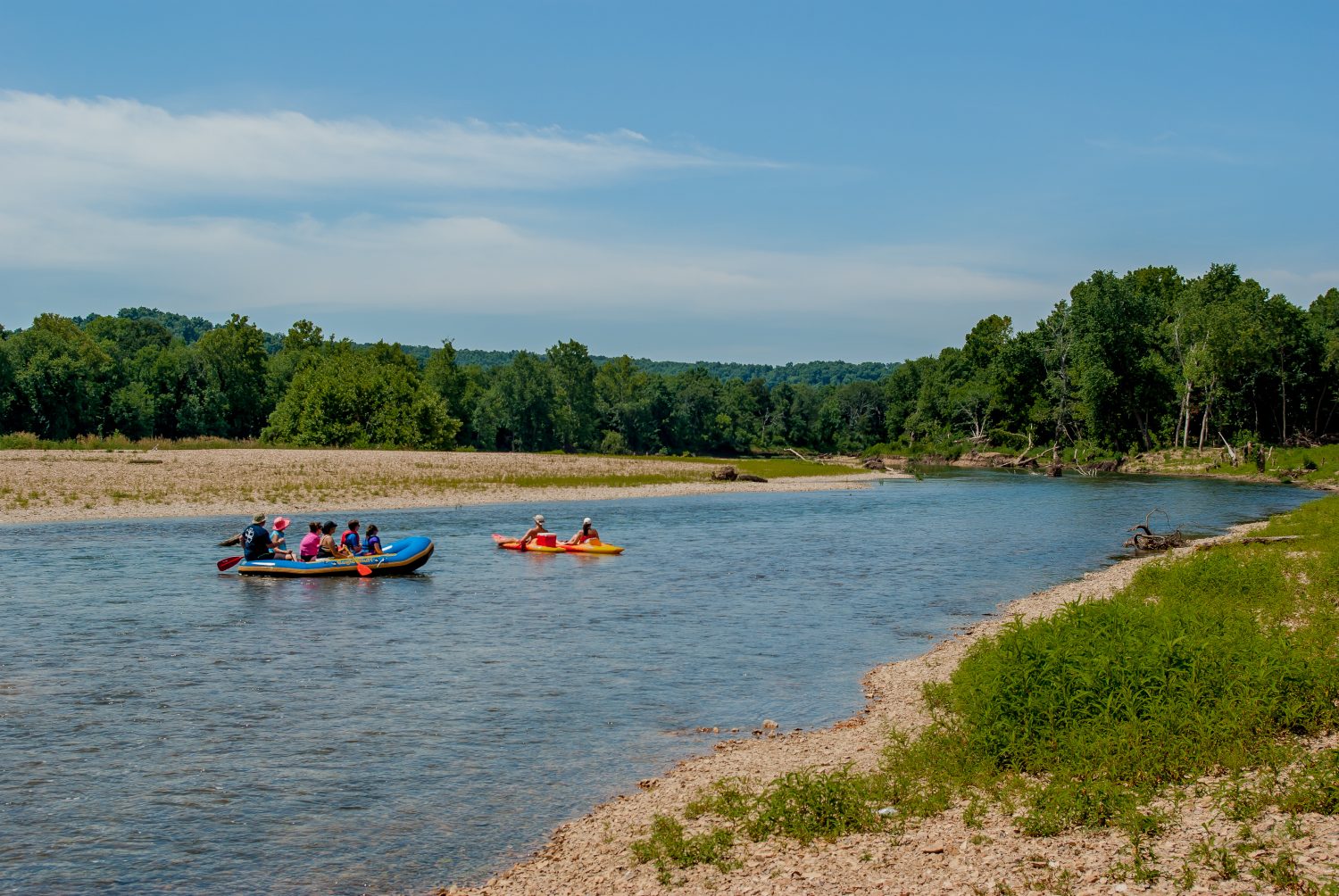 I turisti fanno rafting lungo il fiume in una giornata estiva con alberi e cielo blu