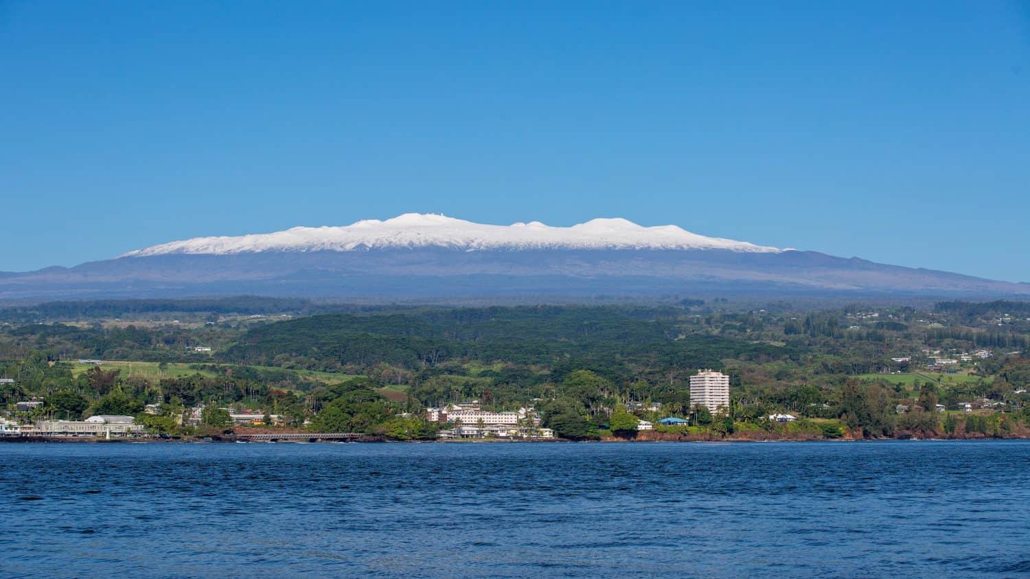 Immagine di Hilo, Hawaii, in una giornata di sole con il Mauna Kea innevato sullo sfondo 