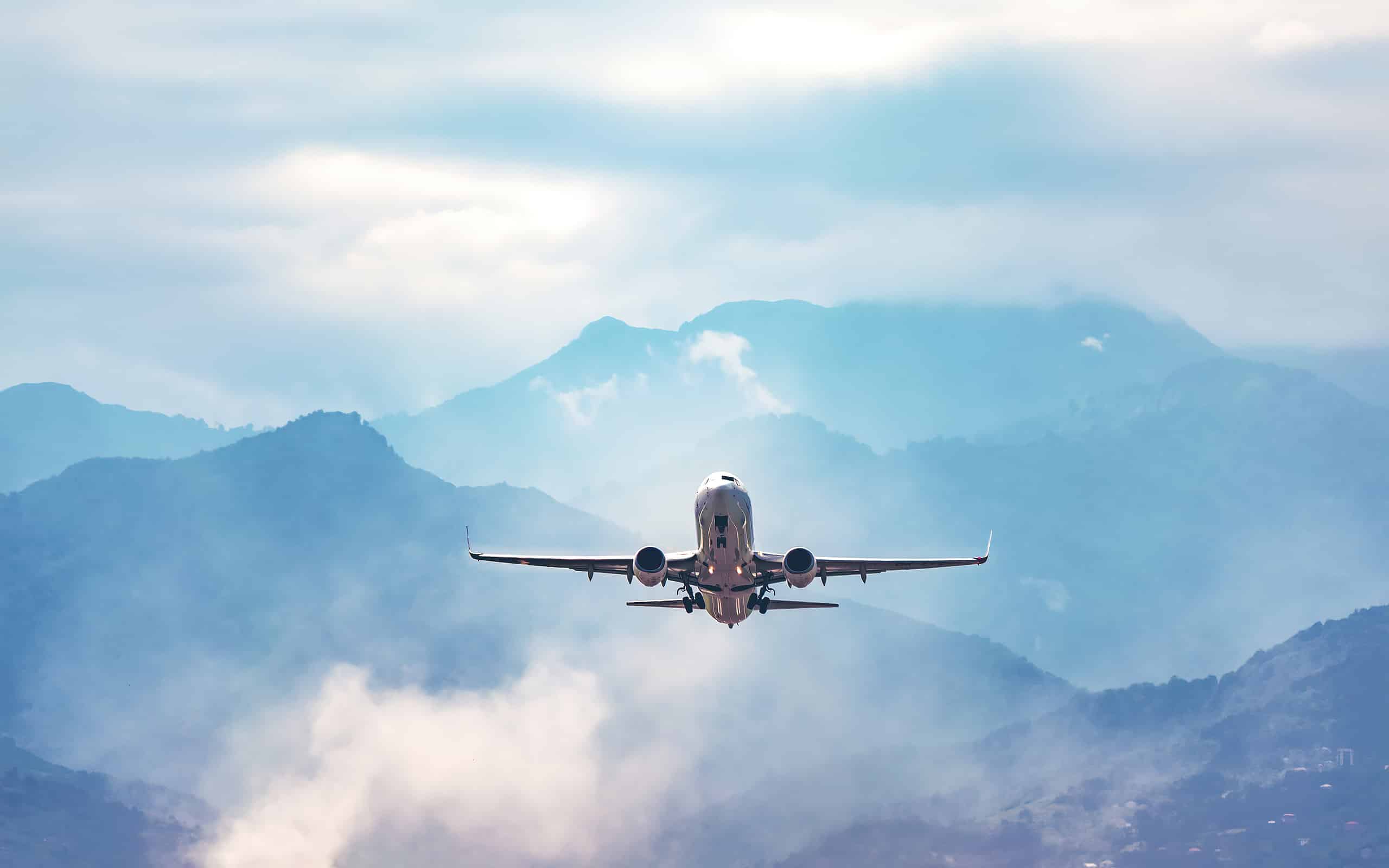 Foto d'archivio del concetto di viaggio del volo aereo.  L'aereo vola sopra un'incredibile montagna nebbiosa blu
