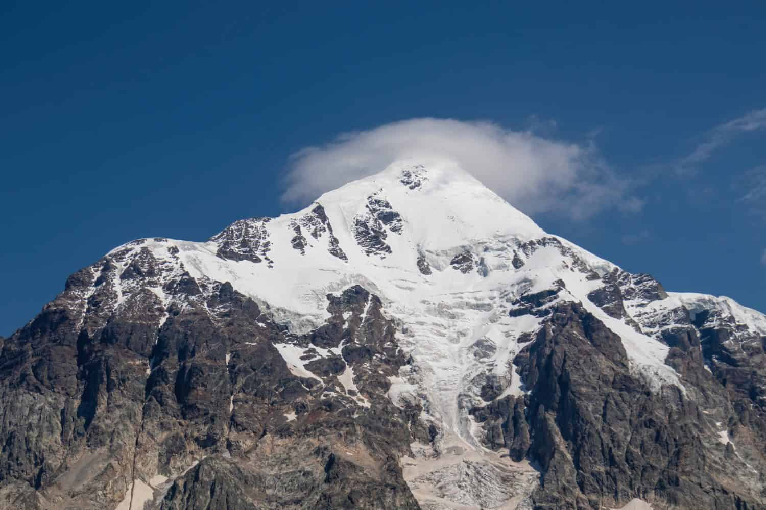 Una vista panoramica sulla vetta innevata di Tetnuldi nella catena montuosa del Grande Caucaso in Georgia, nella regione di Svaneti.  Un ghiacciaio sta scendendo lungo il pendio della montagna.  Picchi aguzzi, voglia di viaggiare, solitudine.