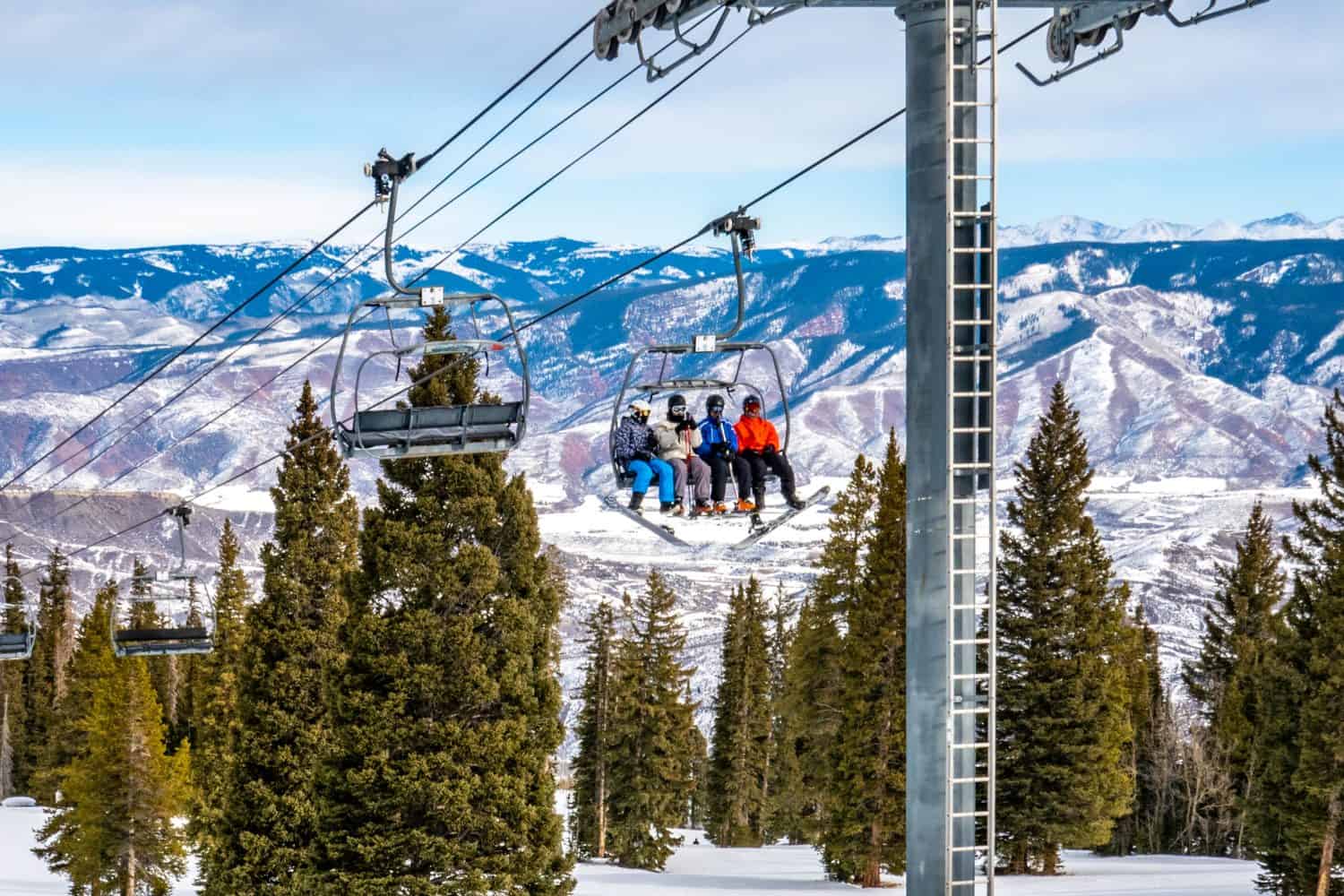 Sciatori e snowboarder salgono sulla seggiovia Alpine Springs presso la stazione sciistica di Aspen Snowmass, nelle Montagne Rocciose del Colorado, in una giornata invernale parzialmente nuvolosa. 