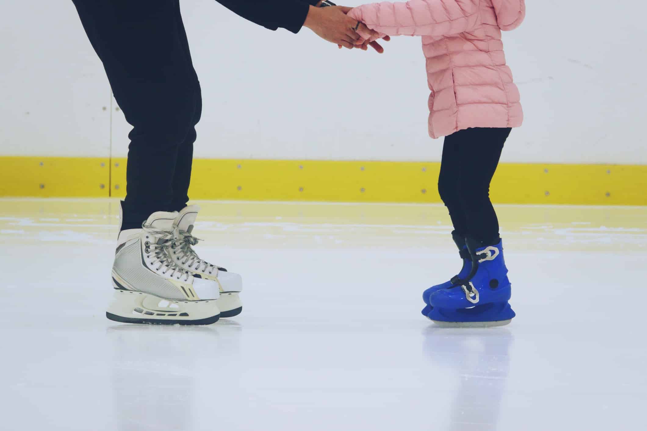 padre che insegna alla figlia a pattinare sulla pista di pattinaggio sul ghiaccio