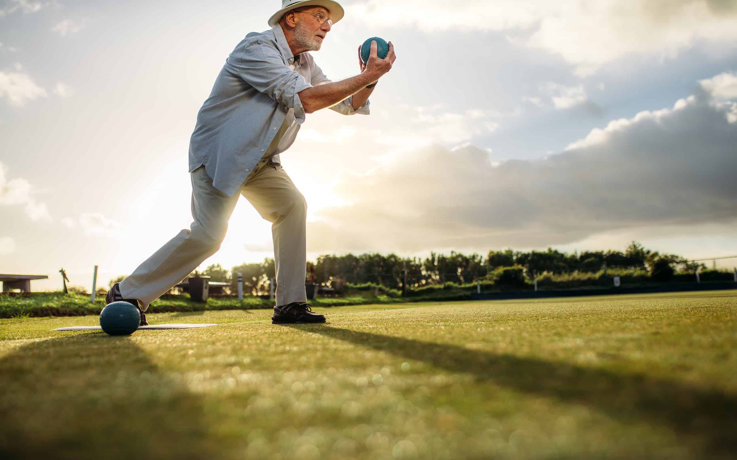 Uomo in procinto di lanciare una palla da bocce attraverso un prato.