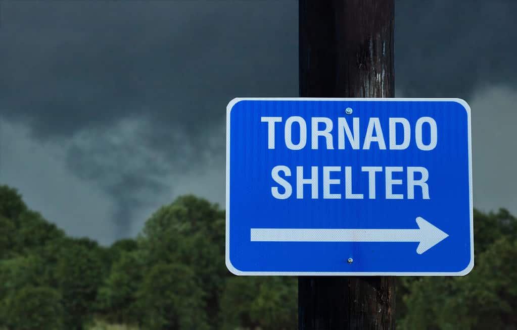 Cartello per rifugio tornado con una piccola nuvola a imbuto sullo sfondo - concetto di pericolo immediato in condizioni meteorologiche avverse e in cerca di riparo