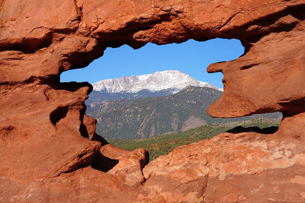 Vista del picco di Pikes attraverso il foro nella formazione rocciosa rossa dei gemelli siamesi nel parco Garden of the Gods a Colorado Springs, Colorado, Stati Uniti