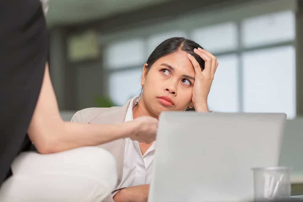 Donna che guarda il suo collega con un'espressione scontenta, donna che lavora nel suo ufficio