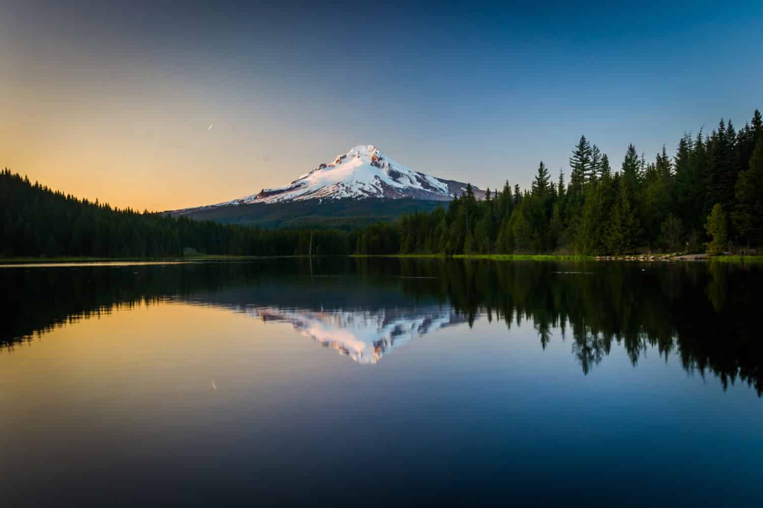 Mount Hood si riflette nel lago Trillium al tramonto, nella foresta nazionale di Mount Hood, Oregon.