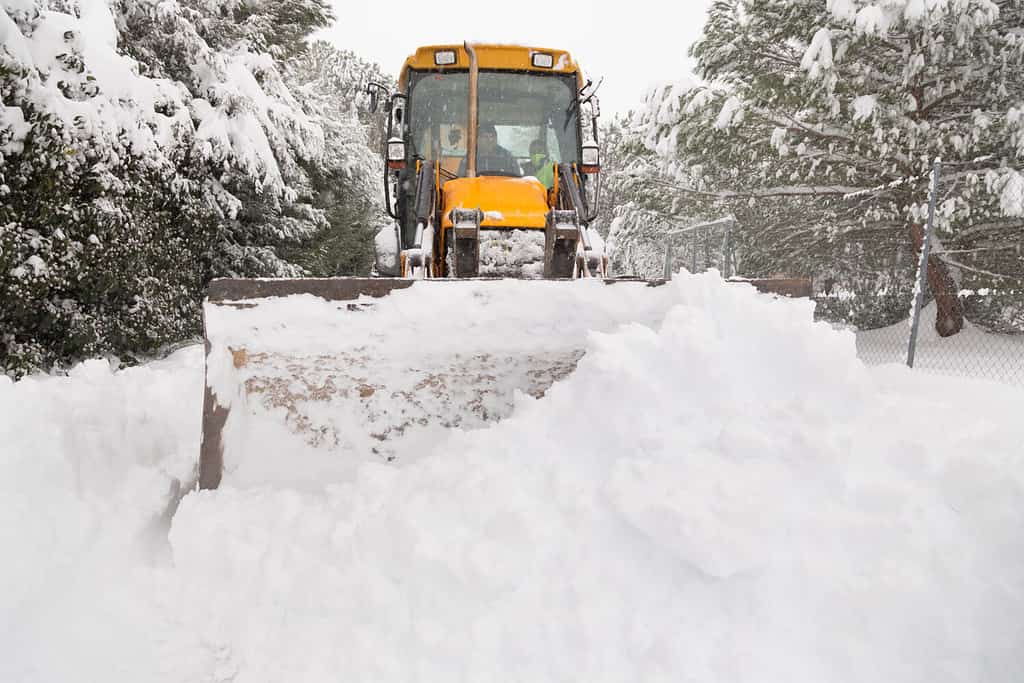 Un trattore giallo rimuove un mucchio di neve da una strada a El Berrueco, Madrid.