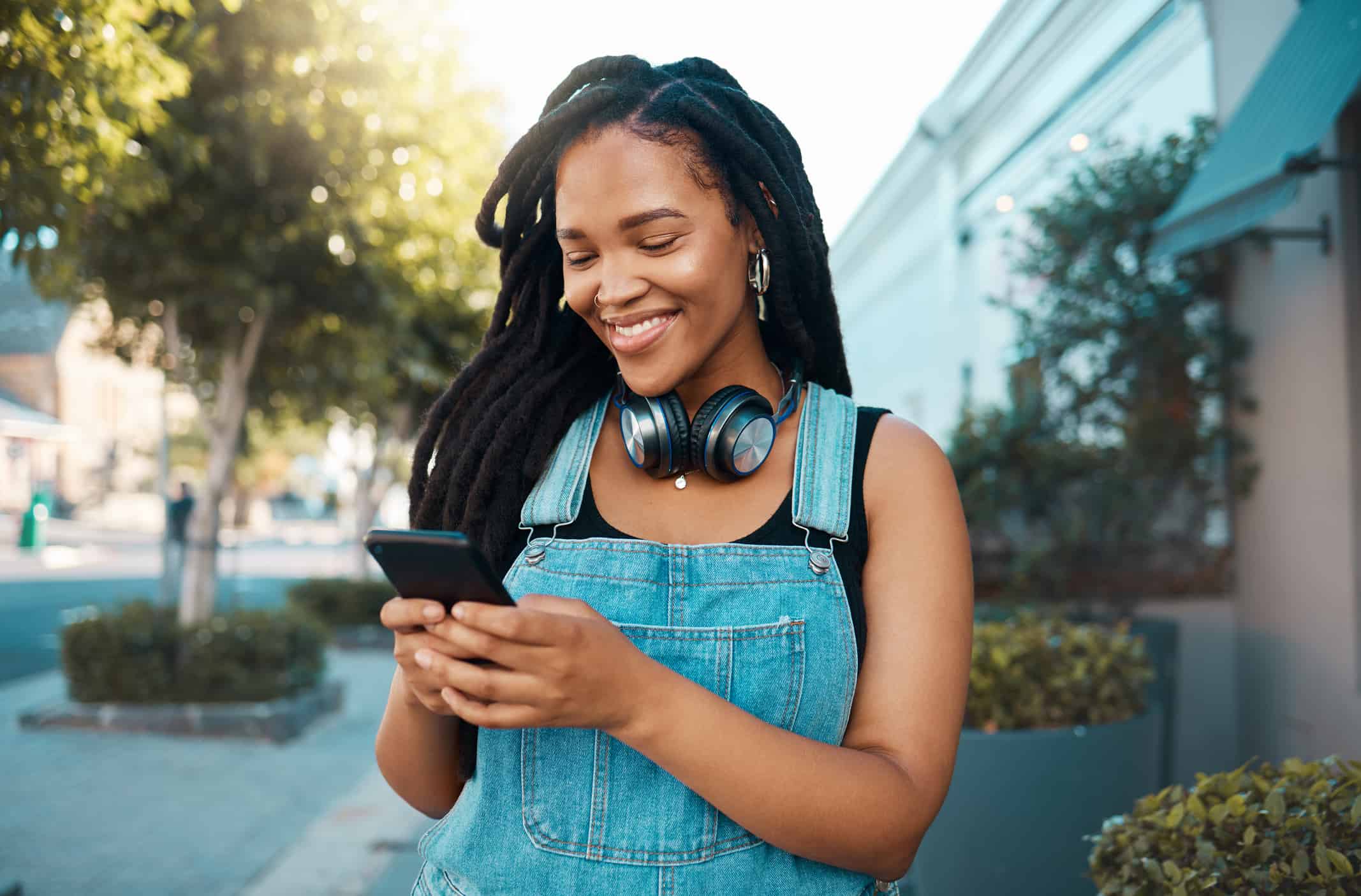 Telefono, social media e musica con una donna in città che usa il cellulare per streaming, audio o comunicazione.  Web, Internet e networking con una giovane donna che legge o digita un messaggio di testo