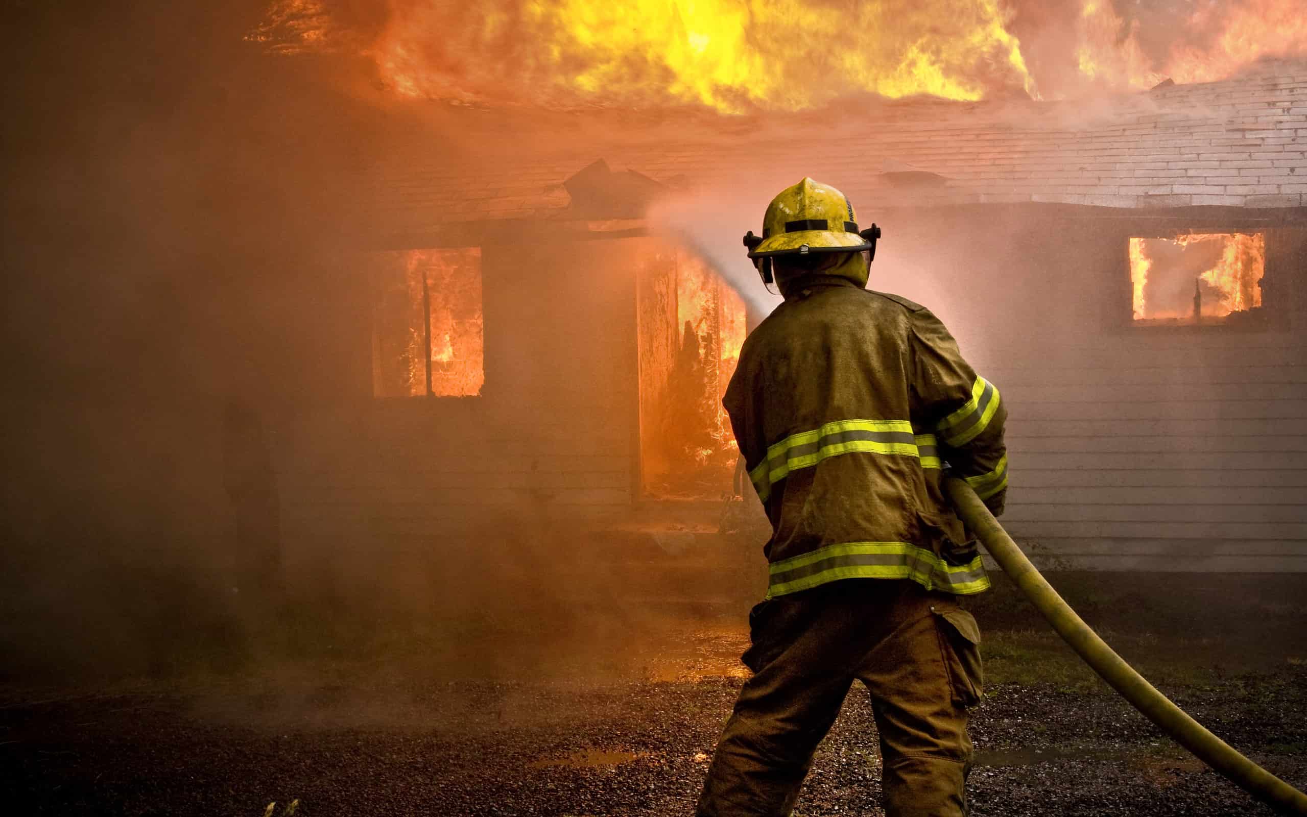 Vigile del fuoco che spruzza acqua durante un incendio in una casa