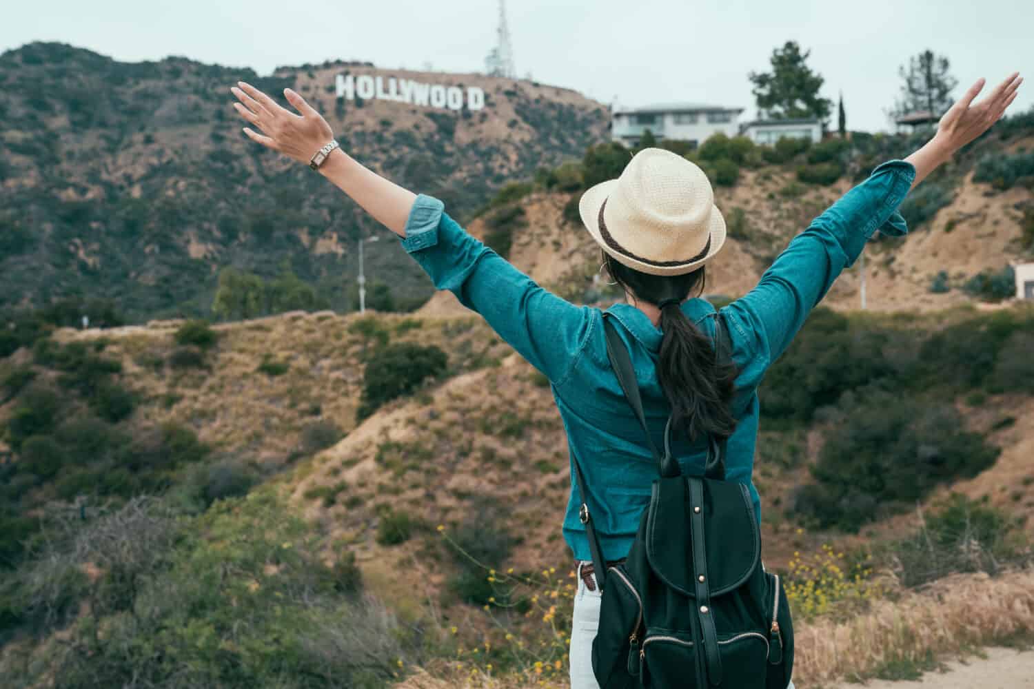 la donna asiatica zaino in spalla ama la libertà spensierata che abbraccia la natura mentre fa un'escursione sulle colline di hollywood e si gode l'aria fresca.  giovane ragazza viaggiatore a braccia aperte alzando in piedi sulla vista panoramica della montagna della primavera.