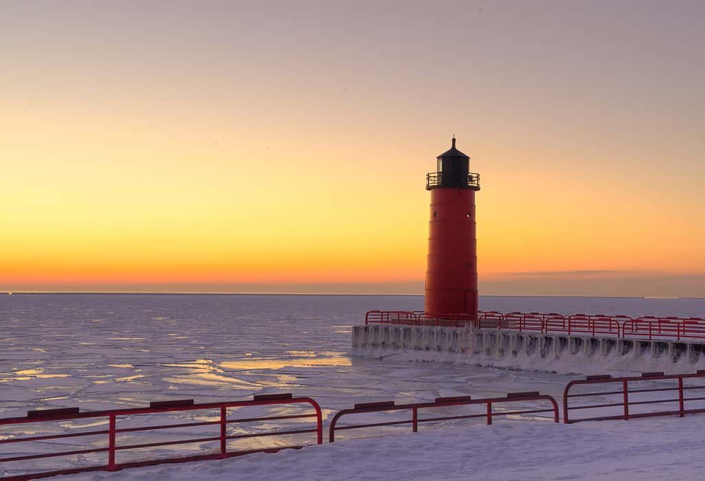 Faro rosso sul lago Michigan in inverno all'alba