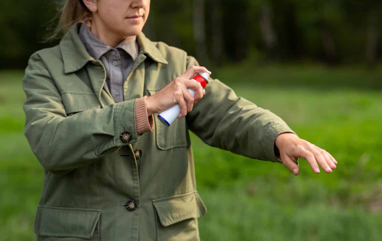 concetto di assistenza sanitaria, protezione e persone - donna che spruzza repellente per insetti o spray per insetti sulla mano al parco