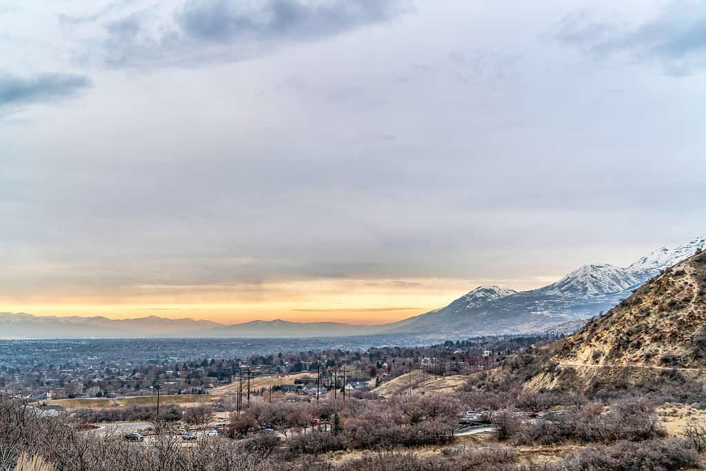 Paesaggio del Provo Canyon Utah con viste panoramiche sulle montagne e sulla valle in inverno.  Il vasto cielo nuvoloso e il tramonto dorato creano uno scenario straordinario per lo scenario.