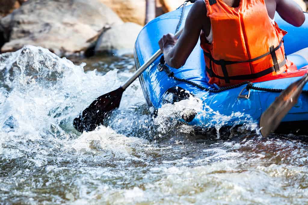 Primo piano di un giovane che fa rafting sul fiume, sport estremo e divertente presso l'attrazione turistica