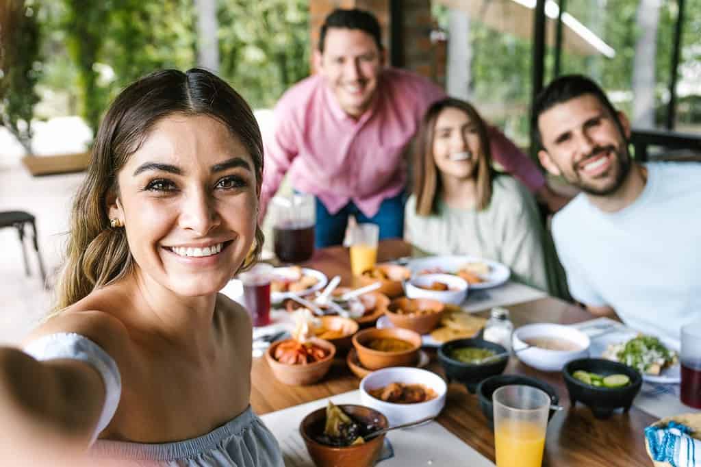Donna messicana che scatta un selfie fotografico con un gruppo di amici latini e mangia cibo messicano nella terrazza del ristorante in Messico America Latina
