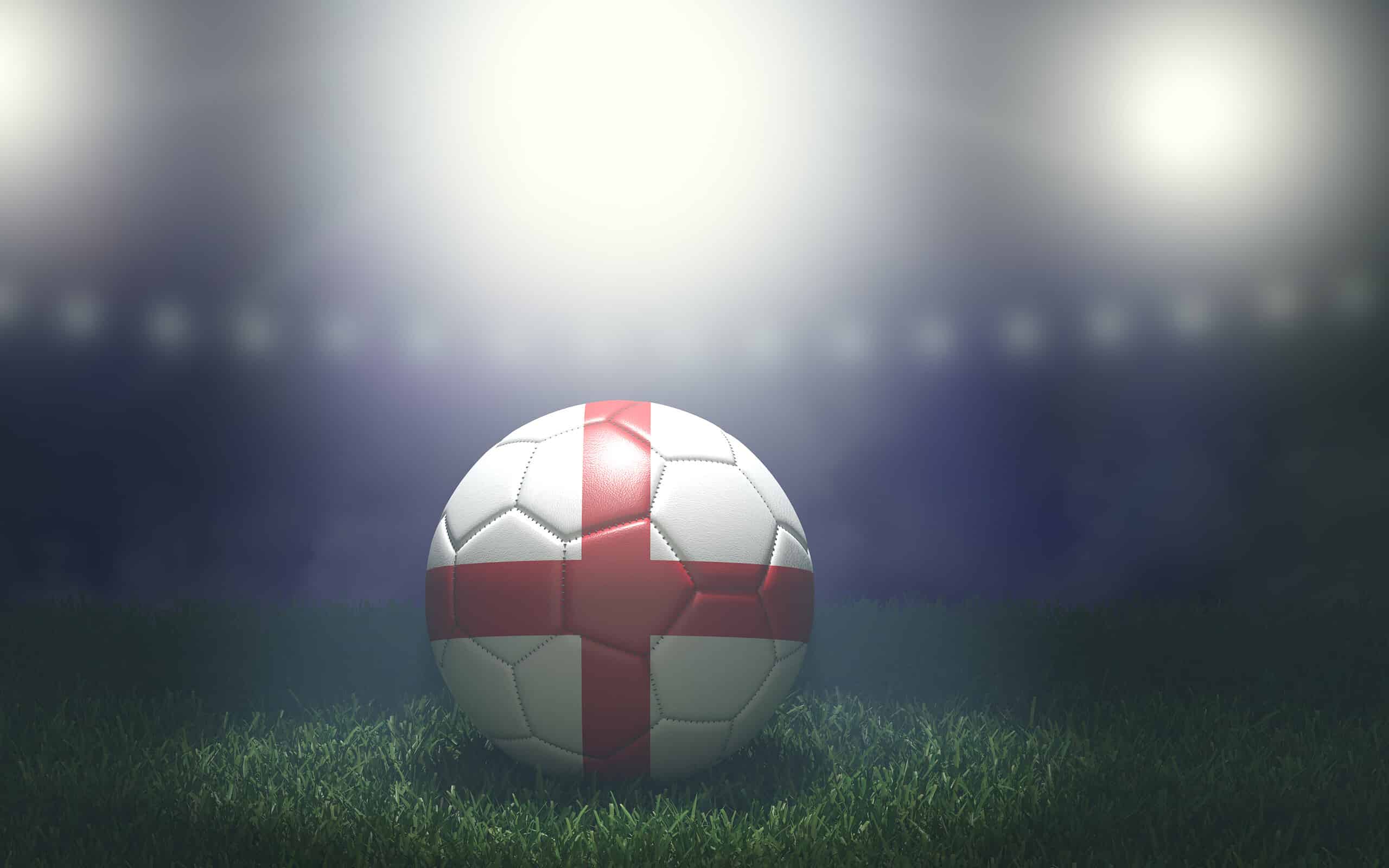Pallone da calcio nei colori della bandiera su uno sfondo luminoso e sfocato dello stadio.  Inghilterra