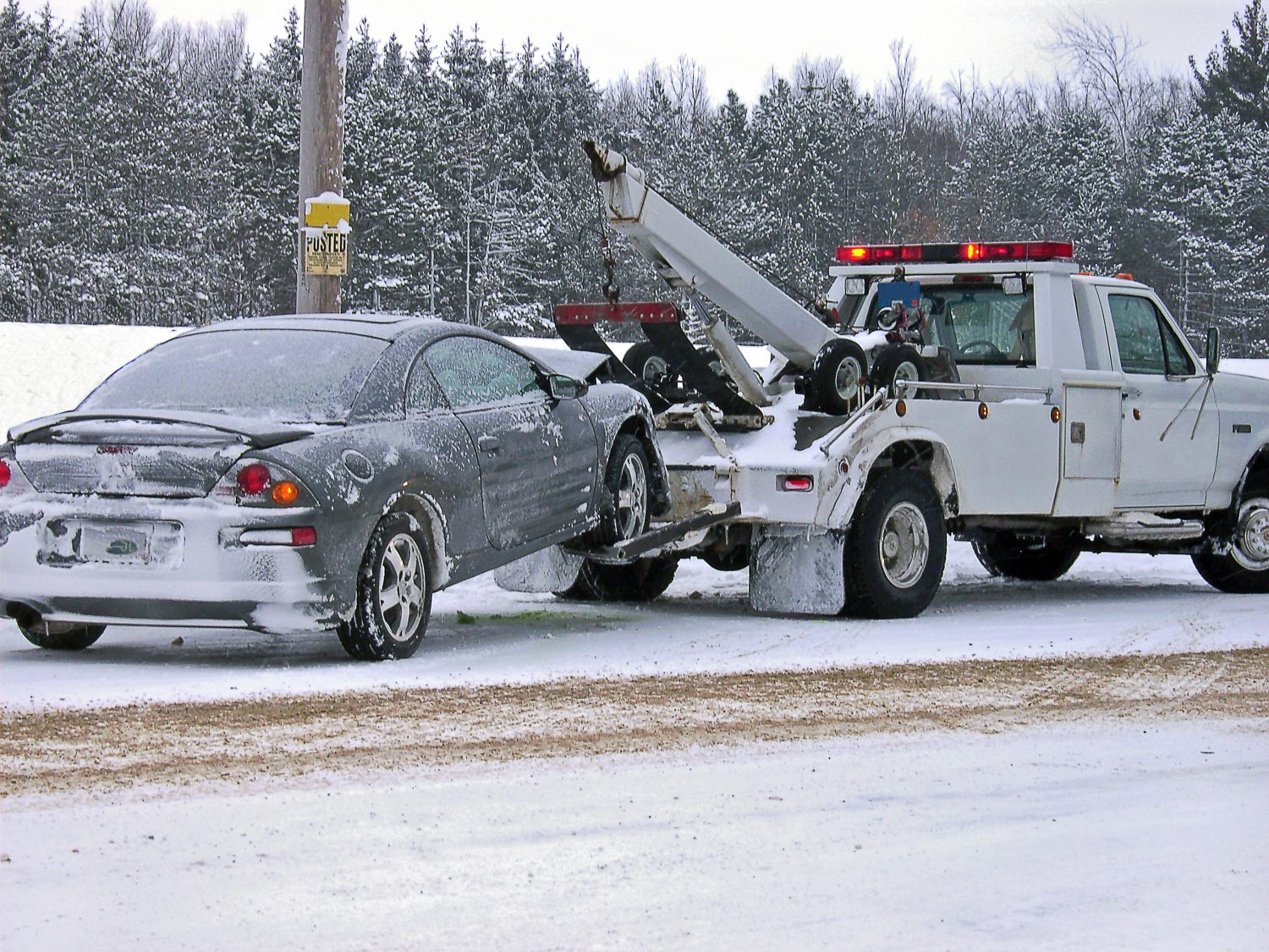 carro attrezzi che traina un'auto distrutta in inverno