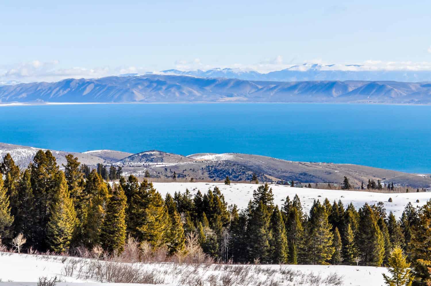 Alberi e neve si stagliano sopra le acque blu del Bear Lake nello Utah.
