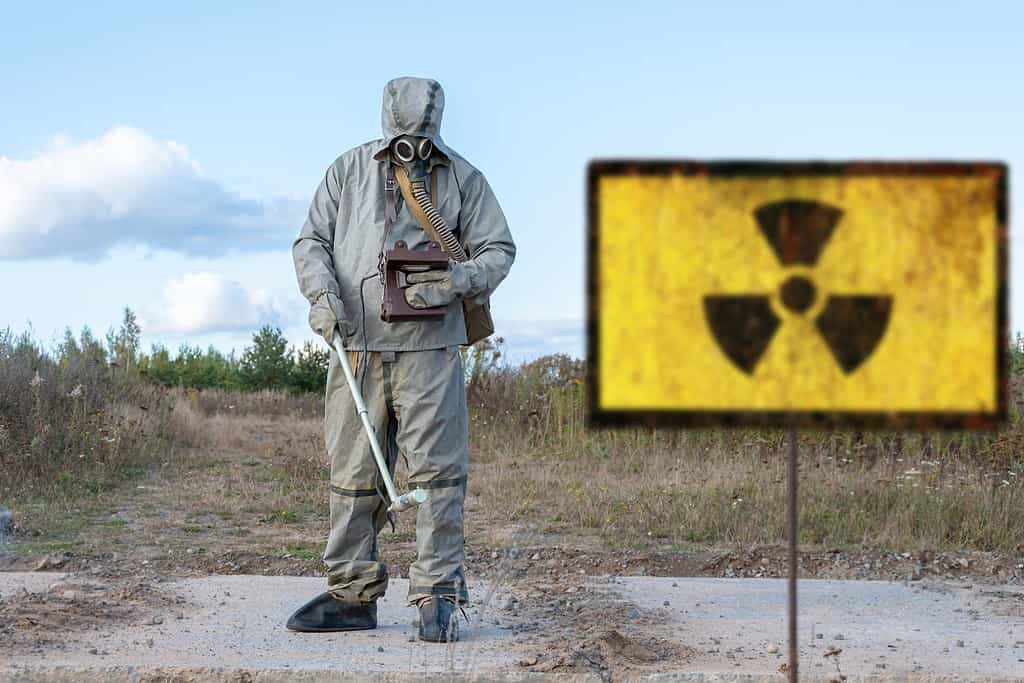la ricognizione chimica militare misura il livello di radiazione, Vecchio segno strutturale di pericolo di radiazioni, sullo sfondo della natura infetta.