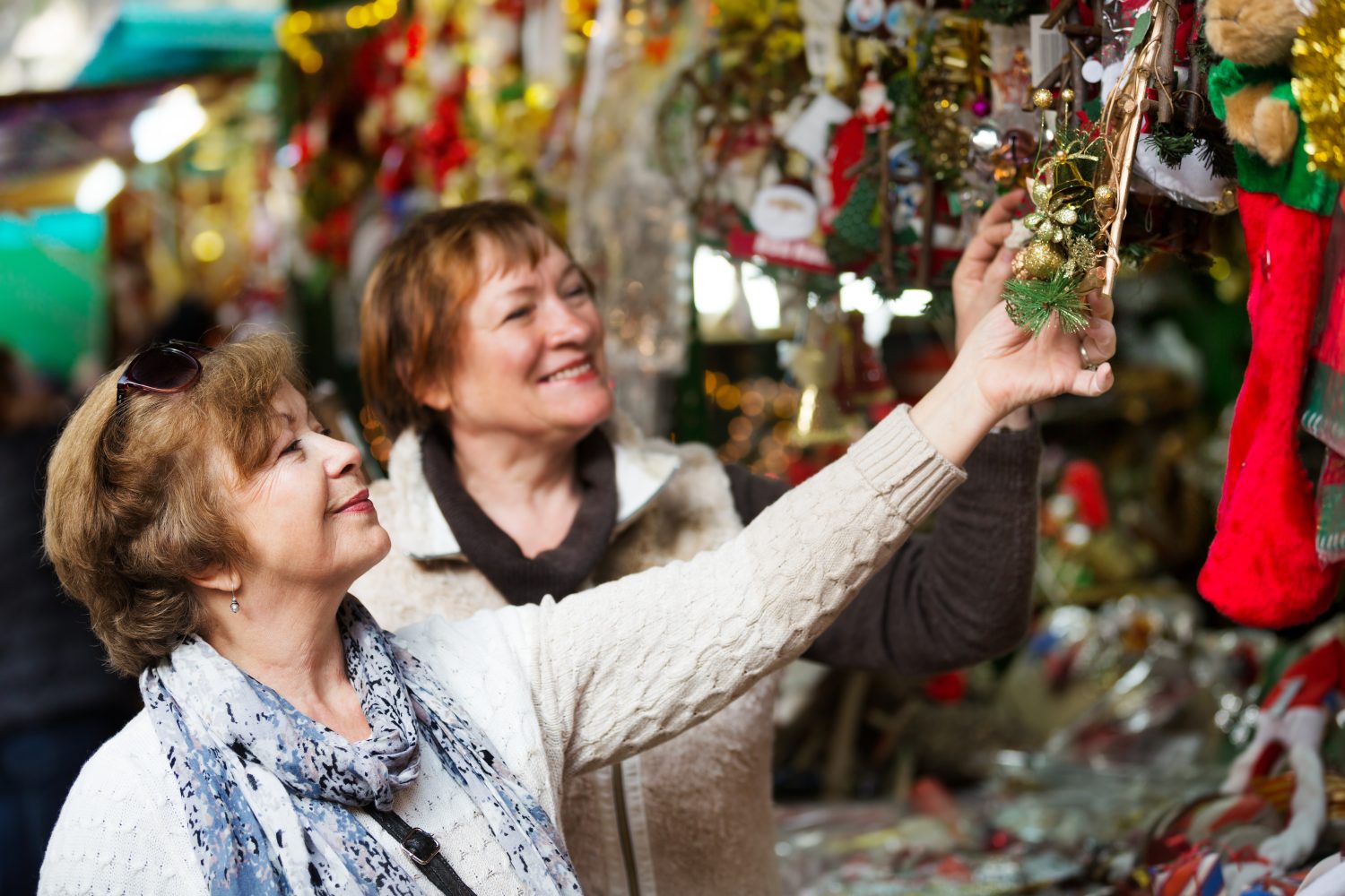Pensionate allegre che acquistano decorazioni e souvenir di Natale in fiera 