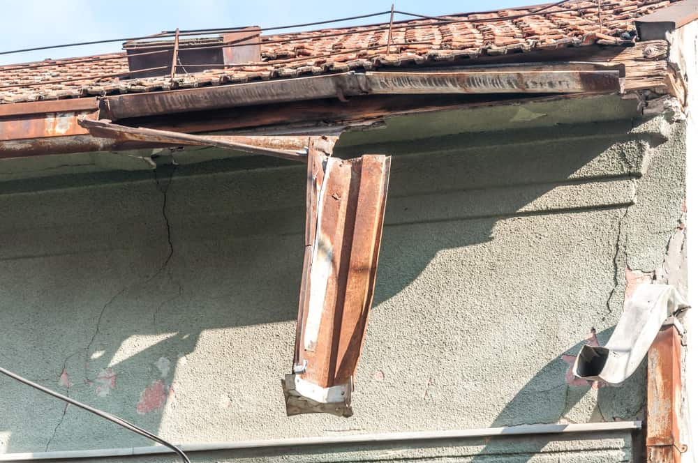 Vecchia grondaia arrugginita rotta e danneggiata sul tetto della casa