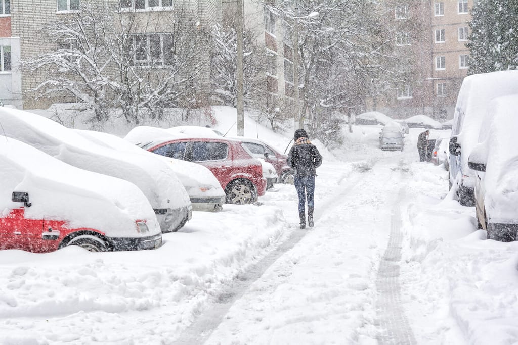 Tempesta di neve, strada innevata e auto con un pedone solitario