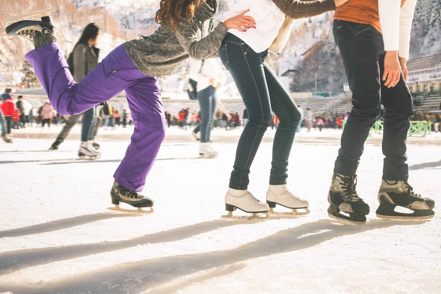 Ragazze adolescenti divertenti e ragazzo che pattinano all'aperto, pista di pattinaggio