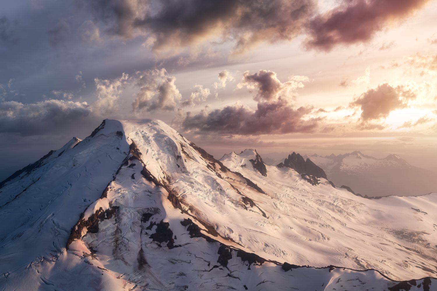 Drammatico paesaggio aereo Vista delle montagne coperte di nuvole durante un tramonto vibrante.  Rappresentazione artistica.  Preso vicino a Mount Baker, a est di Vancouver e Seattle, Washington, Stati Uniti.