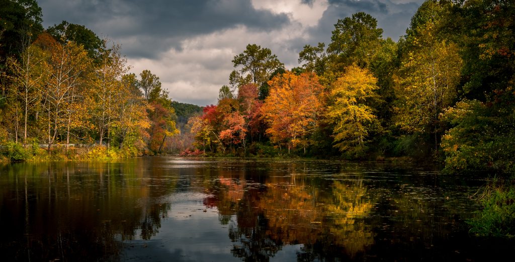 Il vibrante fogliame autunnale si riflette nel lago Swartswood allo Swartswood Lake State Park, Stillwater, New Jersey