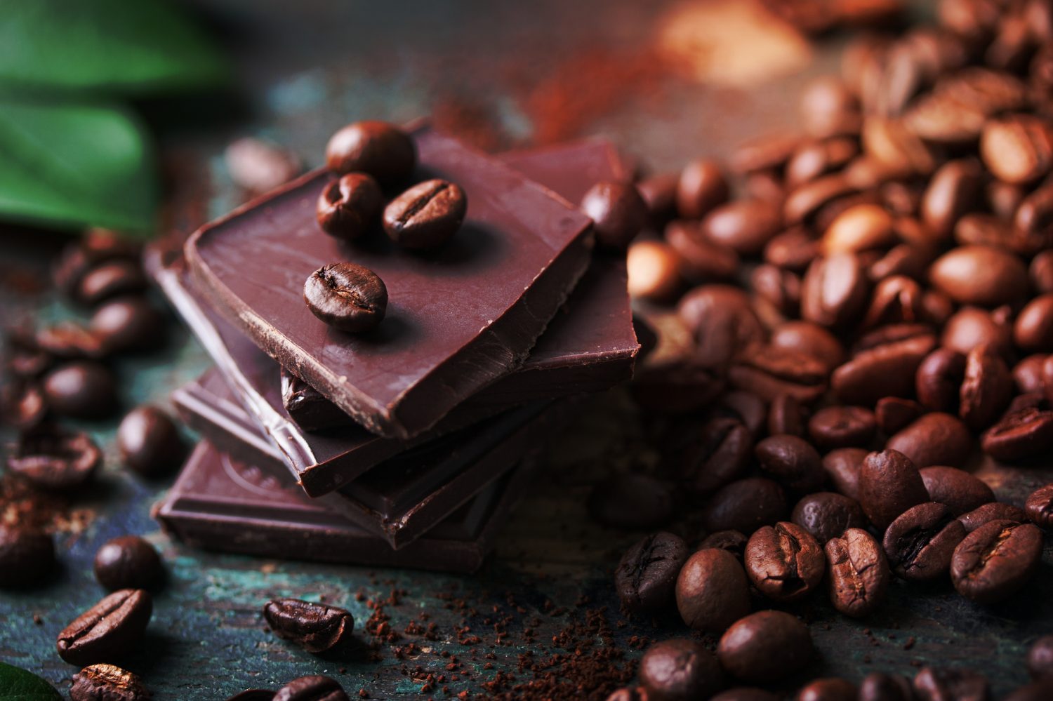Pila di pezzetti di cioccolato con chicchi di caffè su uno sfondo di legno, primo piano