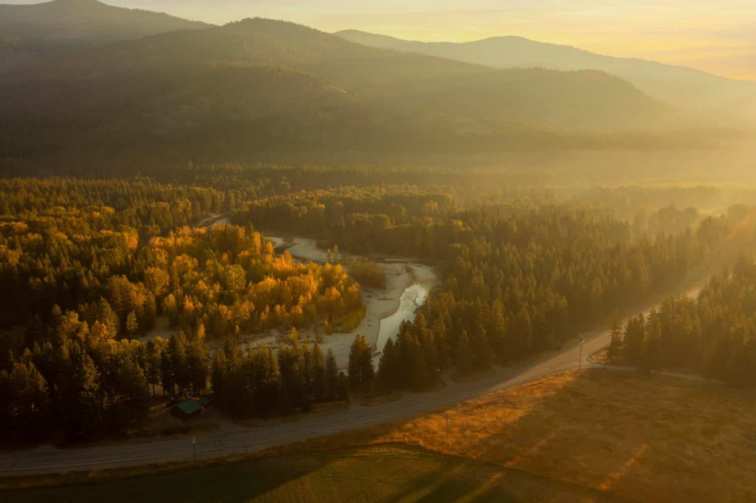 Mattina nebbiosa di caduta sopra il fiume Methow vicino a Mazama, Washington.  Vista aerea dei droni all'alba della storica Methow Valley con viste colorate degli alberi di pioppo tremulo che cambiano nei loro colori autunnali.