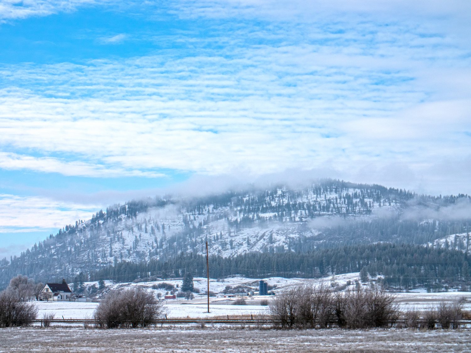 Chewelah Washington USA Terreno agricolo sfondo di montagna Giornata invernale innevata sotto la copertura nuvolosa del cielo blu