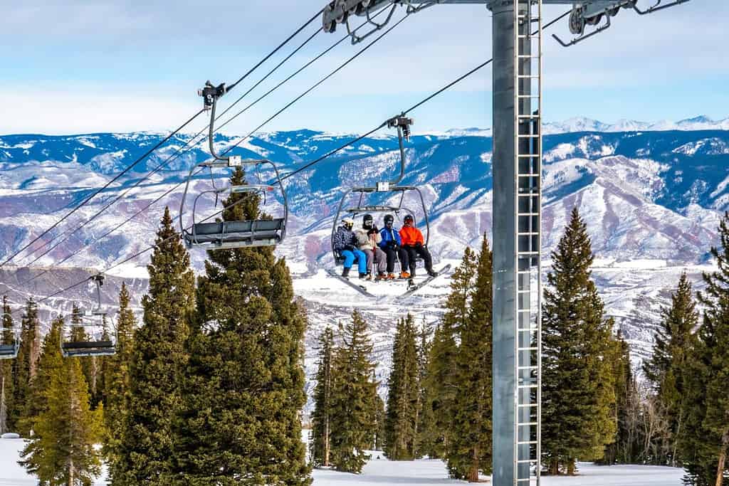 Sciatori e snowboarder salgono sulla seggiovia Alpine Springs presso la stazione sciistica di Aspen Snowmass, nelle Montagne Rocciose del Colorado, in una giornata invernale parzialmente nuvolosa.