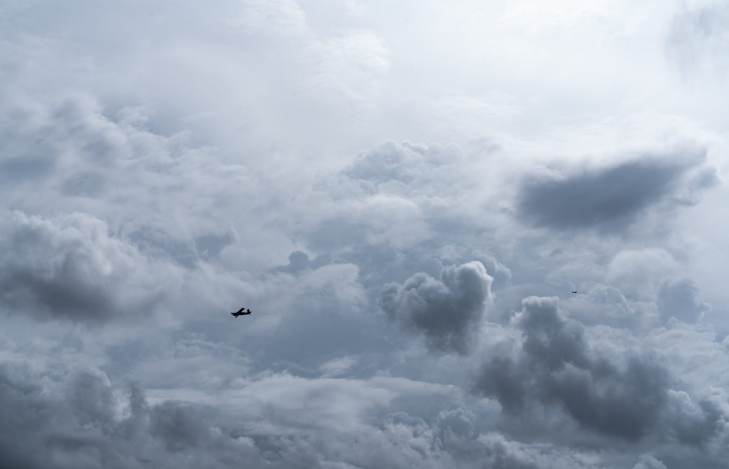 Piccolo aereo nel cielo nuvoloso per la produzione di pioggia.  Nuvole bianche e soffici con piccoli aerei per produrre piogge artificiali.  Due aerei che volano sul cielo nuvoloso.  Aereo agricolo per precipitazioni artificiali.