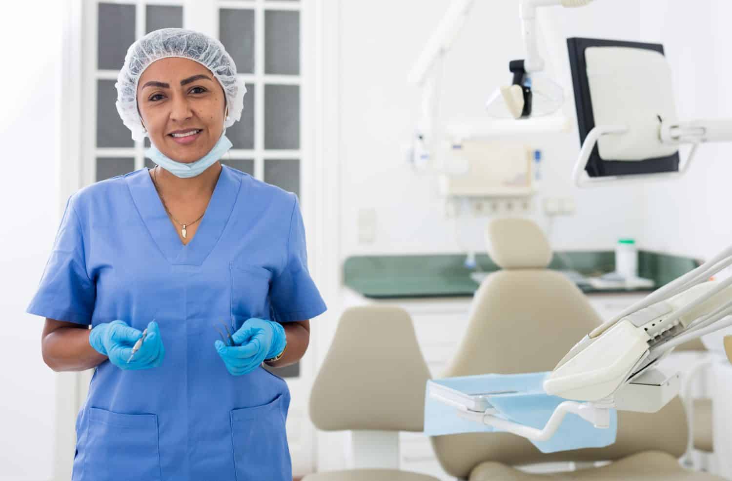 Ritratto del dentista femminile nel centro medico in piedi vicino alla sedia