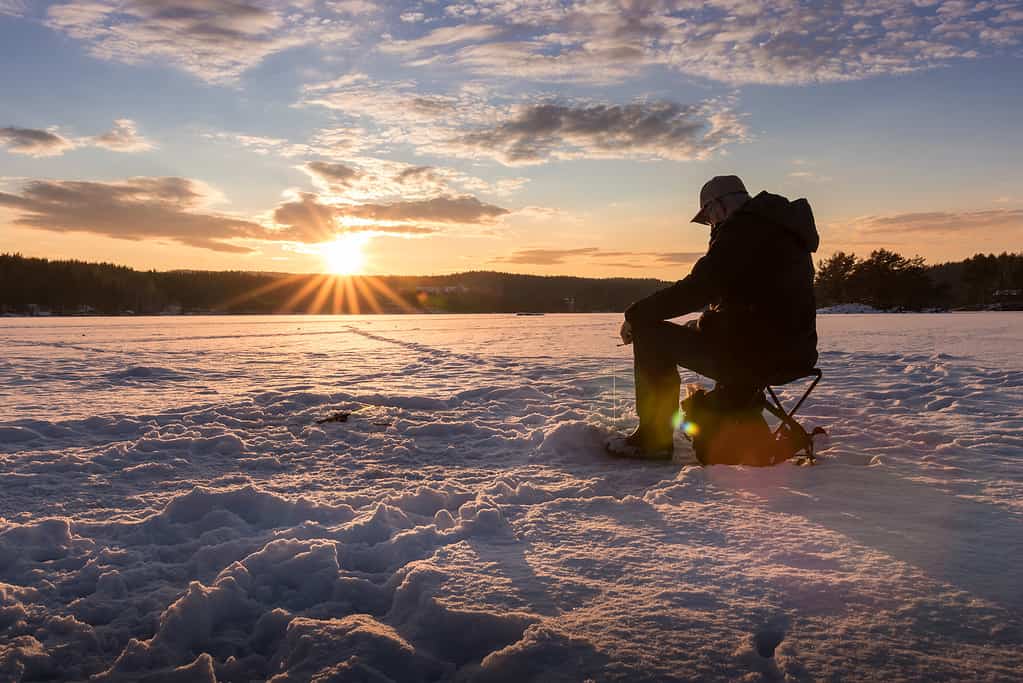 Pesca sul ghiaccio su un lago in Norvegia al tramonto.
