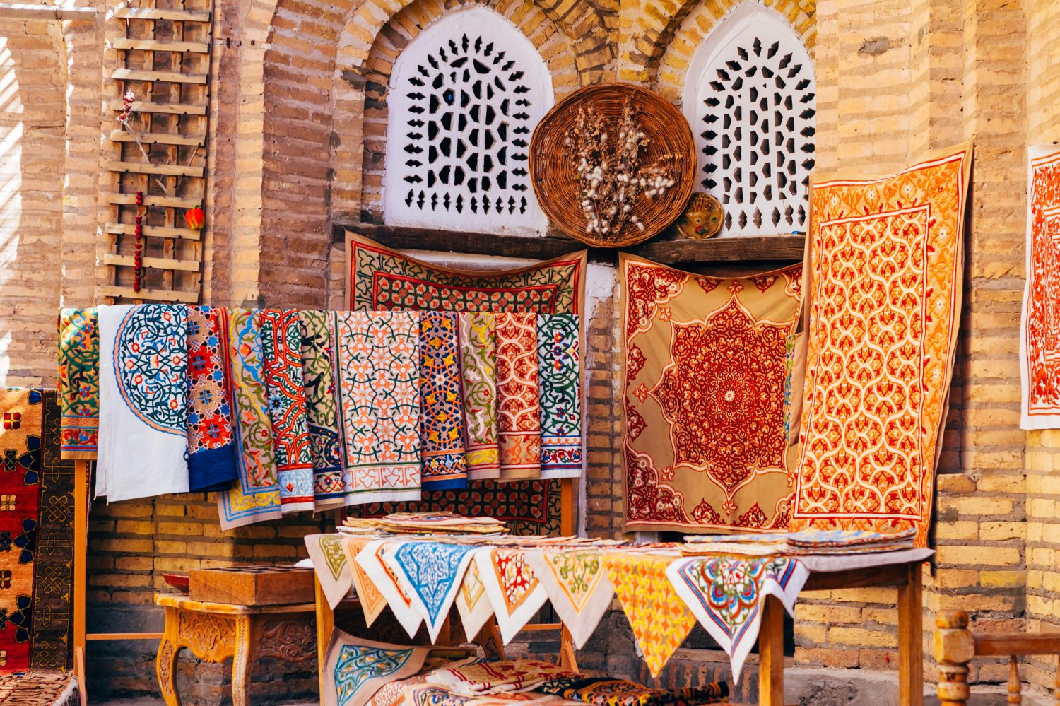 La vasta gamma di tappeti fatti a mano, tradizionali tappeti di seta uzbeki annodati, tovaglie ricamate e biancheria da letto nel piccolo bazar, Khiva, Uzbekistan, Asia centrale