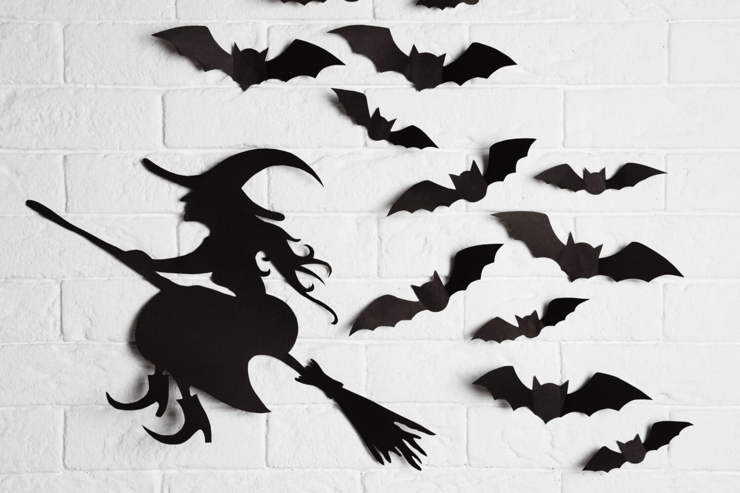 Pipistrelli di carta e ritaglio di streghe sul muro di mattoni.  Arredamento di Halloween