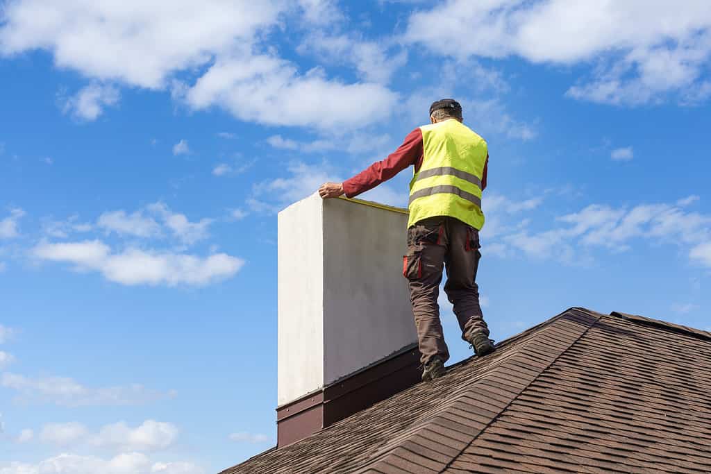 Uomo che misura il camino sul tetto di una nuova casa in costruzione