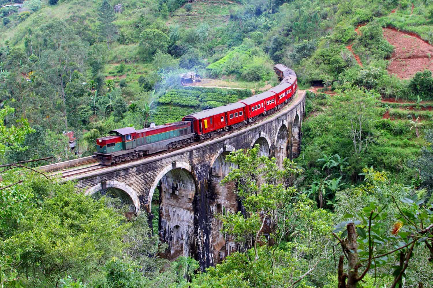 Il treno rosso con la locomotiva a vapore viaggia da Ella a Nuwara Eliya e Kandy sul vecchio ponte dei Nove Archi in paesaggi montani nella giungla.  Provincia di Uva, Sri Lanka