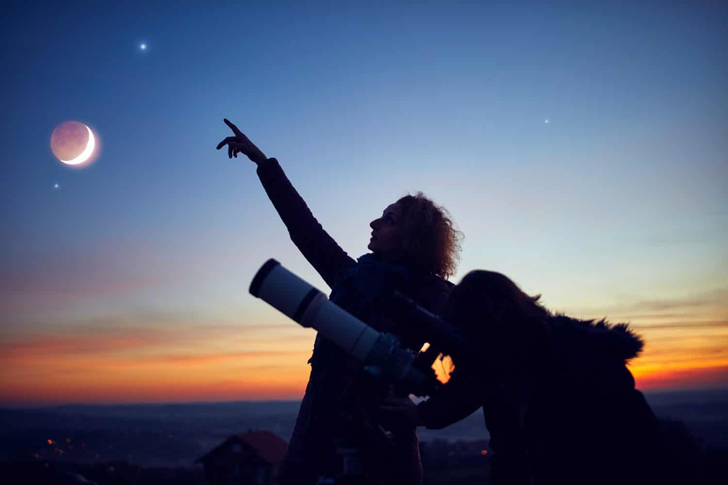 Madre e figlia osservano le stelle, i pianeti, la Luna e il cielo notturno con il telescopio astronomico.