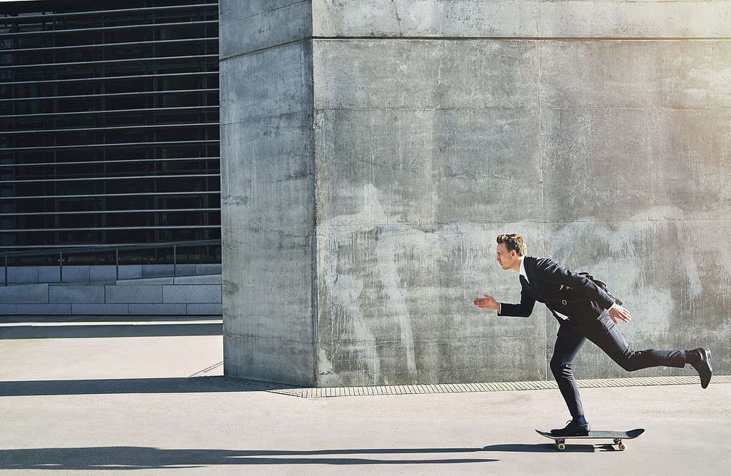 Uomo d'affari su uno skateboard che va avanti velocemente